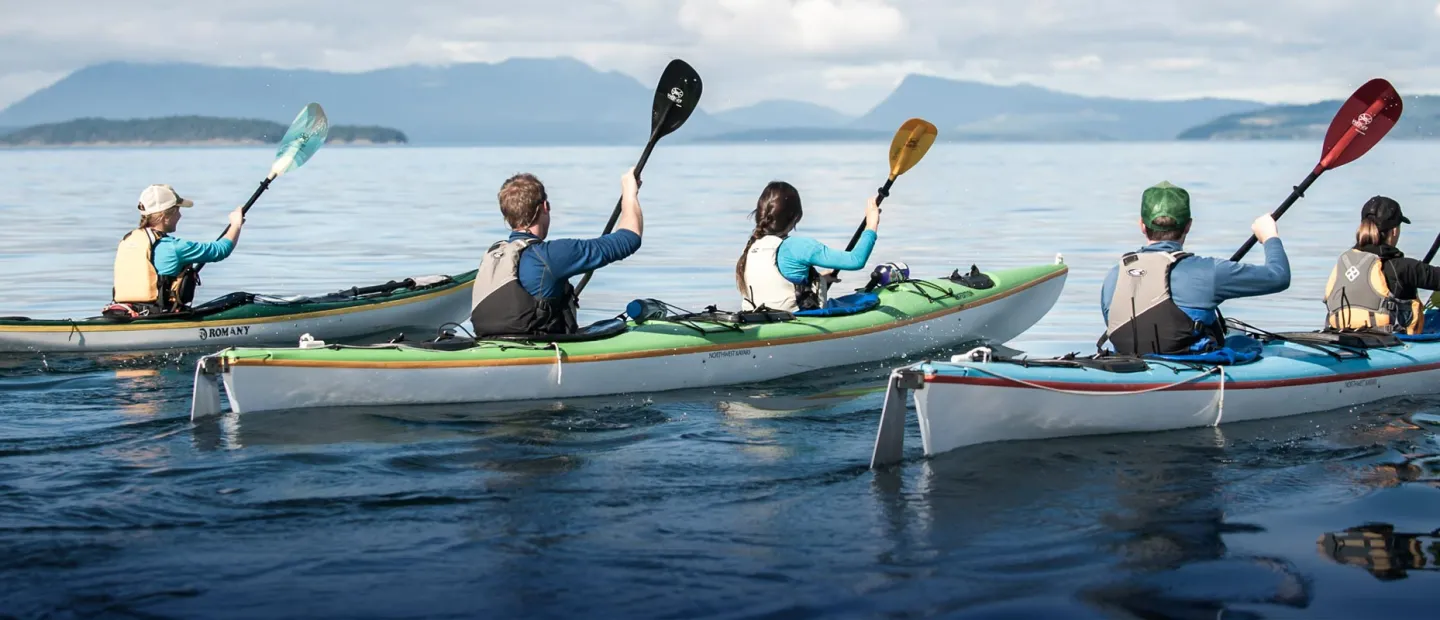 3 sea kayaks with people paddling